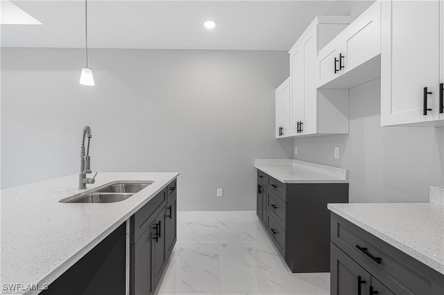 kitchen with white cabinets, light stone countertops, hanging light fixtures, and sink