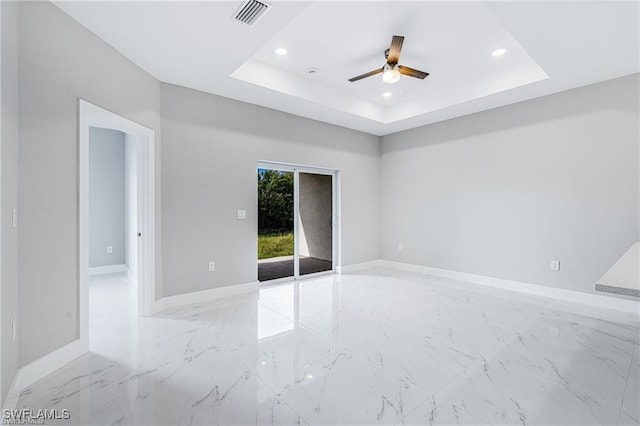 spare room featuring a raised ceiling and ceiling fan