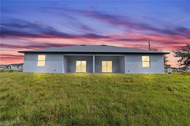 back house at dusk with a lawn