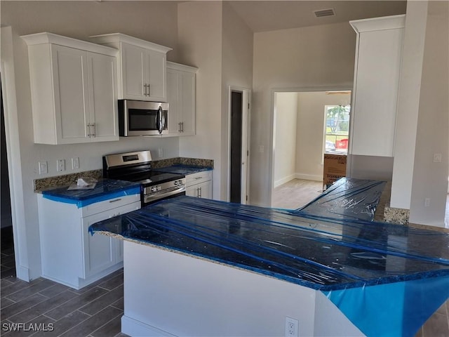 kitchen featuring appliances with stainless steel finishes, wood finish floors, visible vents, and white cabinetry