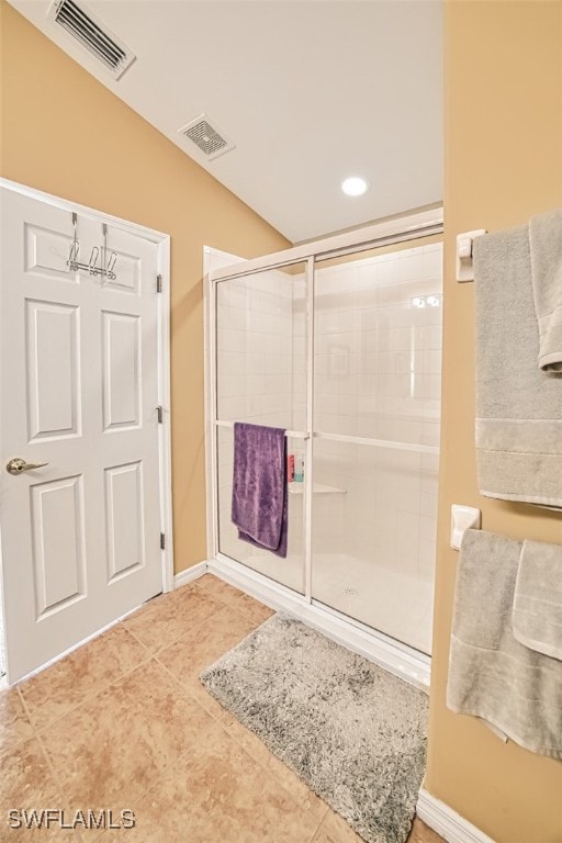 bathroom with tile patterned flooring, vaulted ceiling, and a shower with door