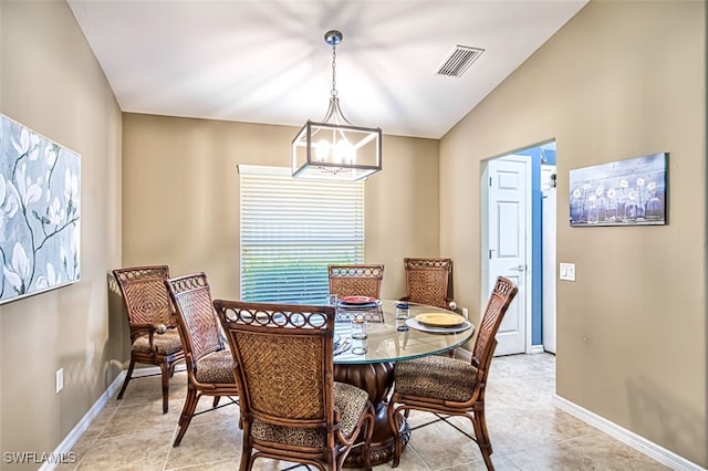 tiled dining space with vaulted ceiling and an inviting chandelier