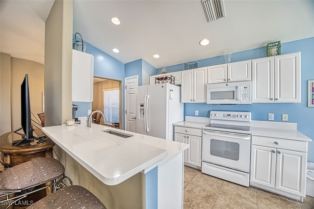 kitchen featuring kitchen peninsula, a kitchen bar, white appliances, sink, and white cabinetry