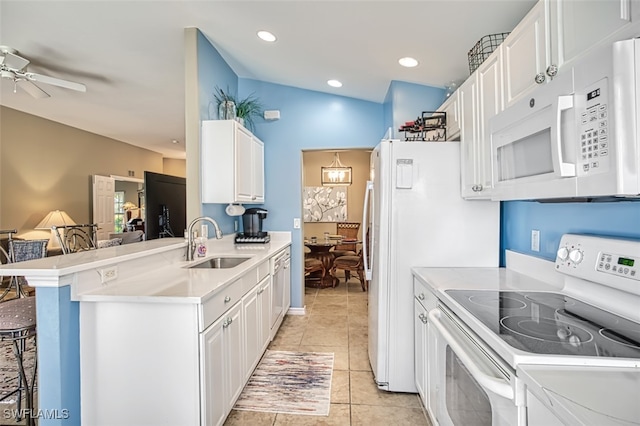 kitchen with white appliances, white cabinets, sink, kitchen peninsula, and a breakfast bar area