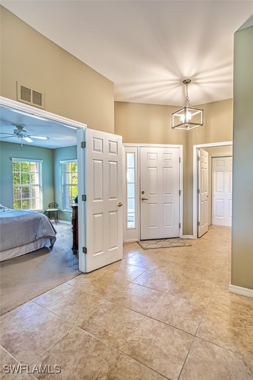 tiled entrance foyer with ceiling fan with notable chandelier