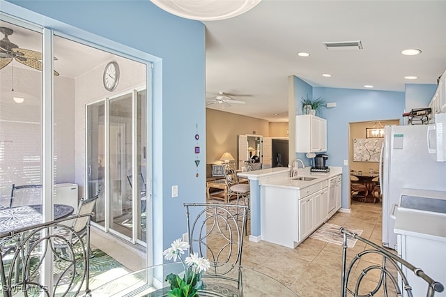 kitchen with white cabinets, sink, ceiling fan, light tile patterned flooring, and kitchen peninsula