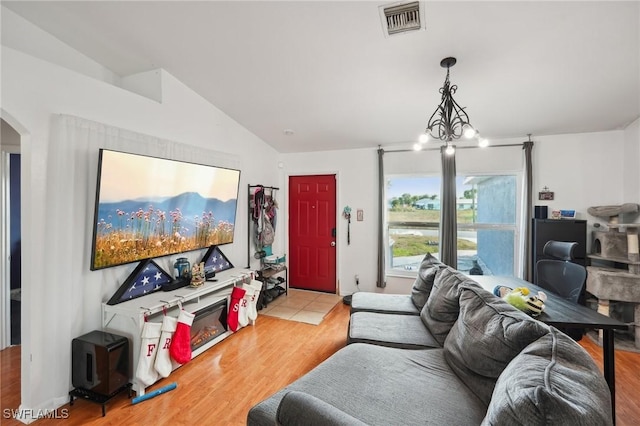 living room featuring a chandelier, light hardwood / wood-style floors, and lofted ceiling