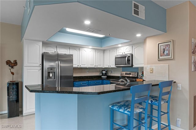 kitchen featuring a kitchen breakfast bar, kitchen peninsula, white cabinetry, and stainless steel appliances