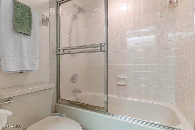 bathroom with toilet and bath / shower combo with glass door