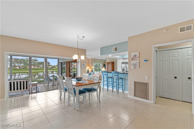 dining room featuring a water view, a chandelier, and light tile patterned floors