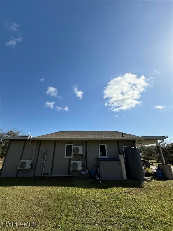 back of property featuring a lawn and ac unit