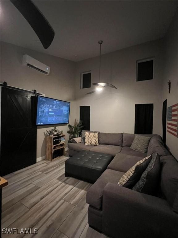 cinema with a barn door, light hardwood / wood-style flooring, and a wall unit AC