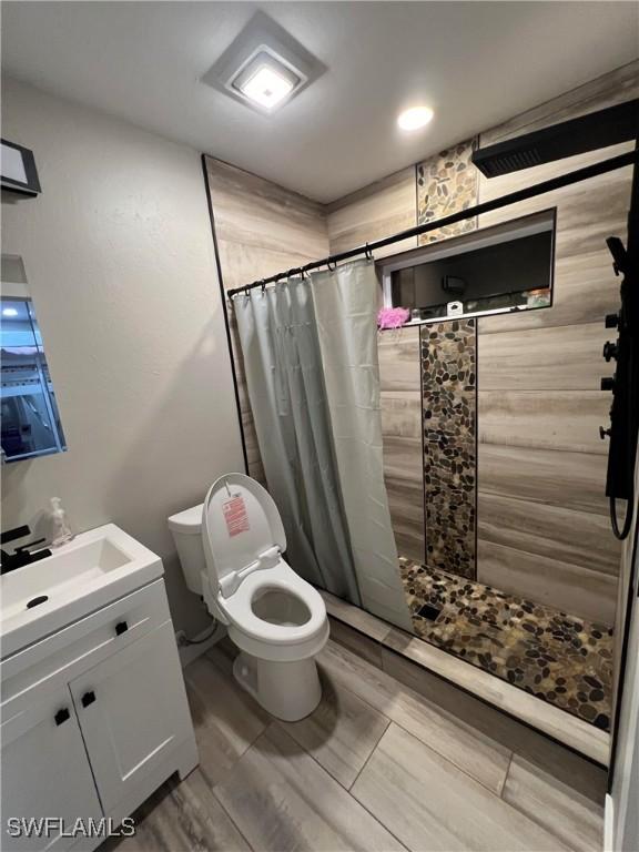 bathroom featuring vanity, toilet, and walk in shower