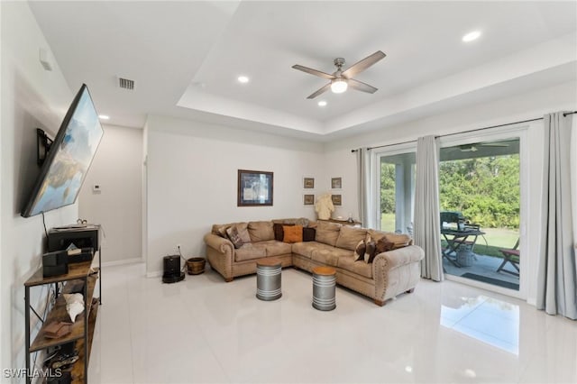 living room featuring a tray ceiling, ceiling fan, and light tile patterned flooring