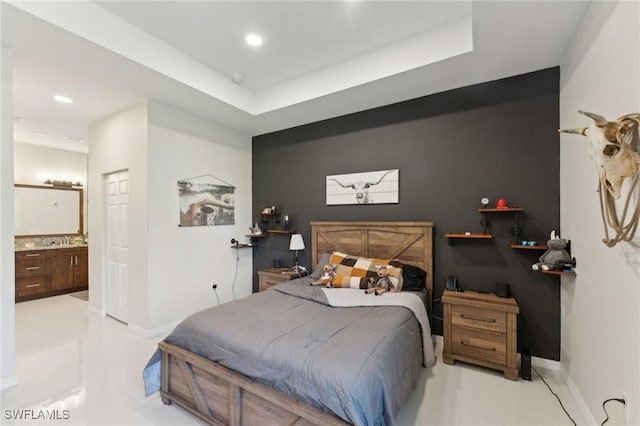 bedroom featuring ensuite bathroom and a tray ceiling