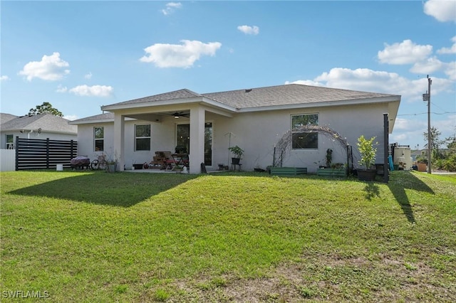 rear view of house featuring a lawn and ceiling fan