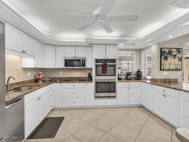 kitchen featuring appliances with stainless steel finishes, dark stone counters, crown molding, sink, and white cabinetry