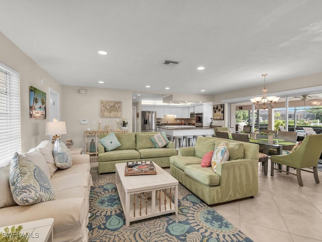 living room with a wealth of natural light, light tile patterned flooring, and a chandelier