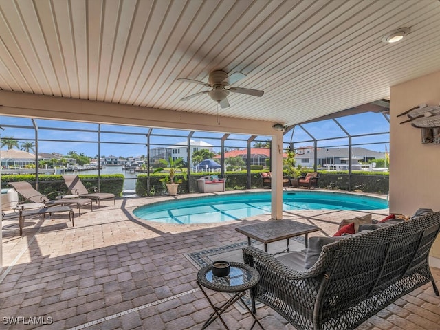 view of pool with ceiling fan, a water view, a patio, and glass enclosure