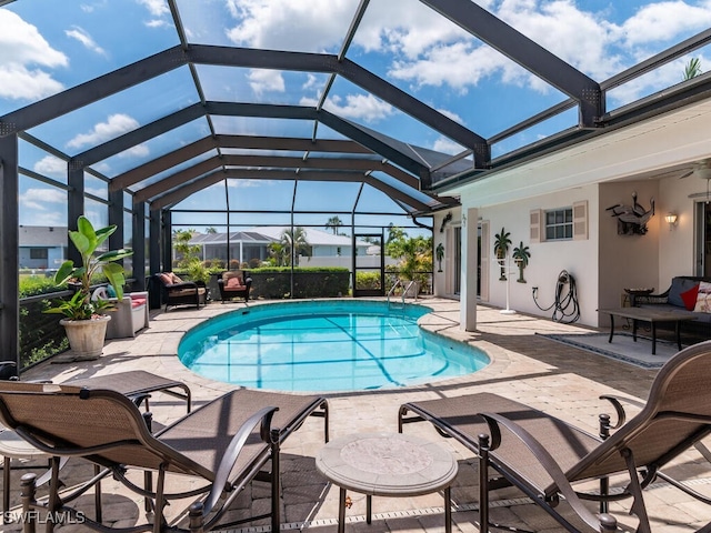 view of swimming pool featuring glass enclosure, ceiling fan, and a patio area