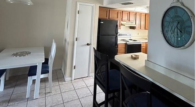 kitchen with black fridge, light tile patterned flooring, and white electric stove