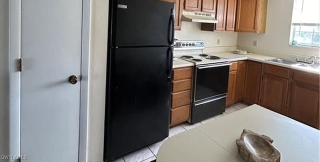 kitchen with electric range, light tile patterned flooring, black fridge, and sink