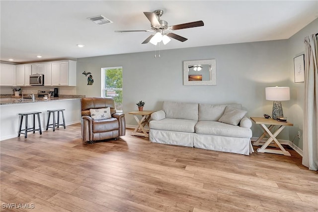 living room featuring light hardwood / wood-style flooring and ceiling fan