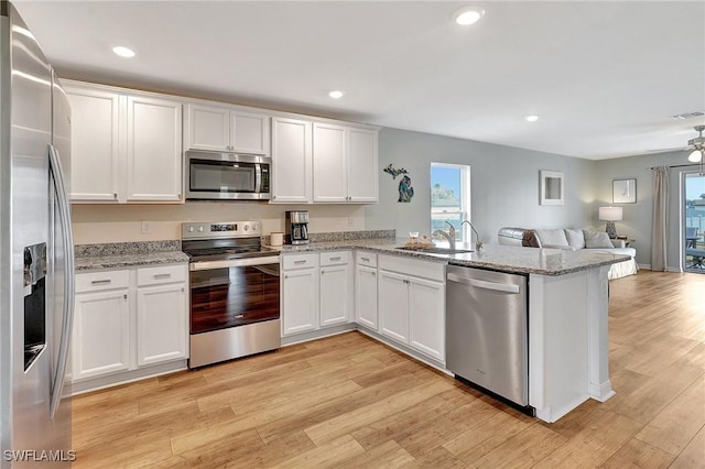 kitchen featuring kitchen peninsula, stainless steel appliances, white cabinets, and sink