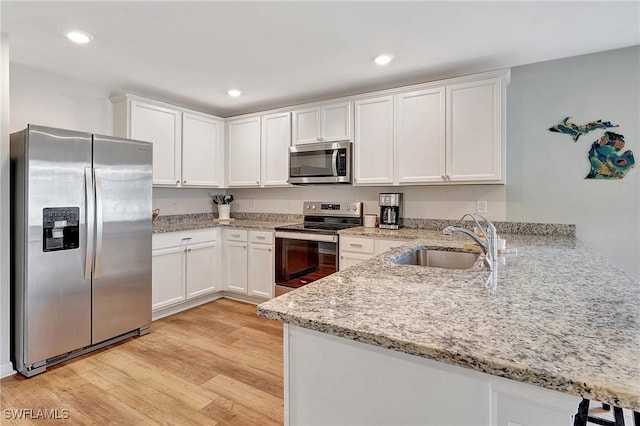 kitchen featuring kitchen peninsula, sink, white cabinets, and appliances with stainless steel finishes