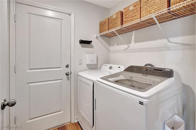 clothes washing area featuring washing machine and clothes dryer and light hardwood / wood-style flooring