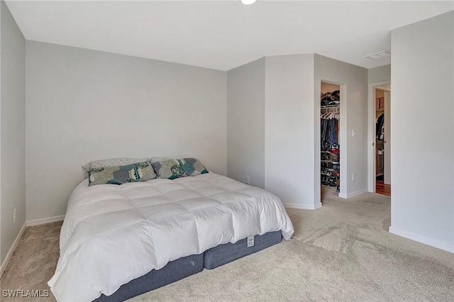 carpeted bedroom with a walk in closet and a closet