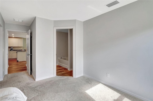 unfurnished bedroom with light colored carpet and sink