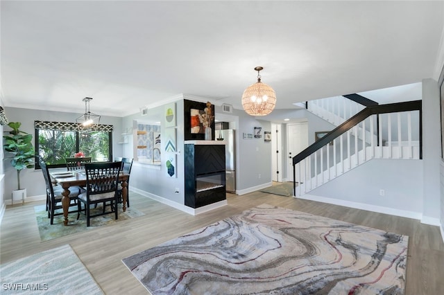 living room with a chandelier, light wood-type flooring, and crown molding