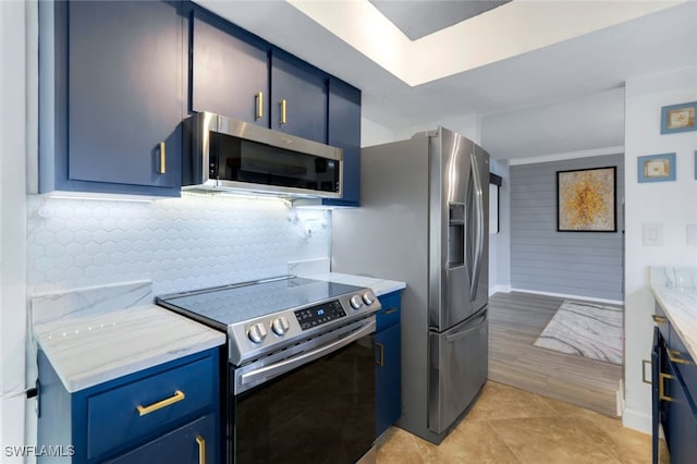 kitchen with blue cabinetry, light stone counters, light tile patterned flooring, and appliances with stainless steel finishes