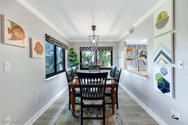 dining room featuring sink, wood-type flooring, and crown molding