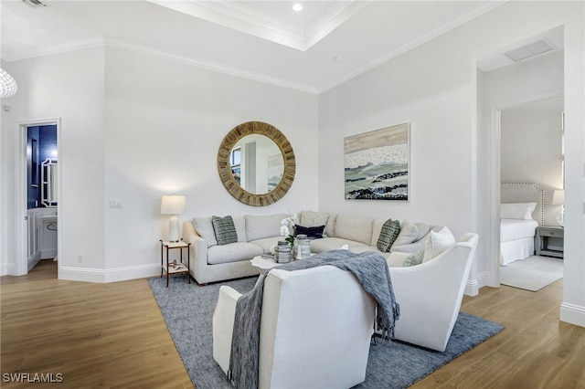 living room with hardwood / wood-style flooring, a raised ceiling, and crown molding