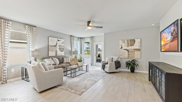 living area with light wood-type flooring, ceiling fan, and baseboards