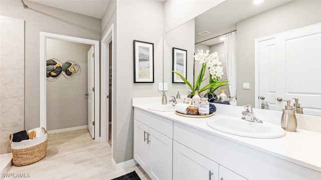 bathroom with double vanity, visible vents, baseboards, and a sink