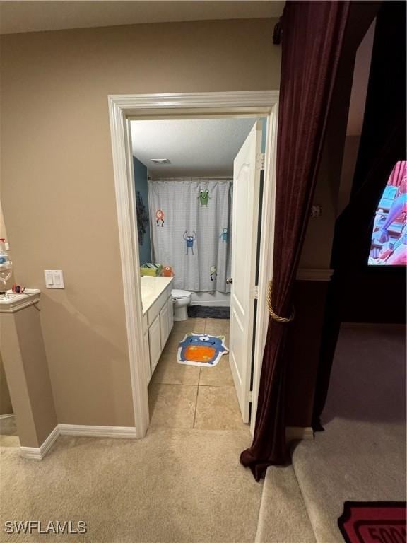 bathroom with curtained shower, tile patterned flooring, toilet, vanity, and baseboards