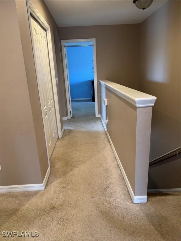 hallway with carpet floors, an upstairs landing, and baseboards