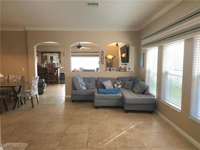 tiled living room with ceiling fan, plenty of natural light, and crown molding