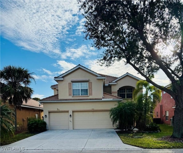 view of front facade with a garage, concrete driveway, a tile roof, and stucco siding