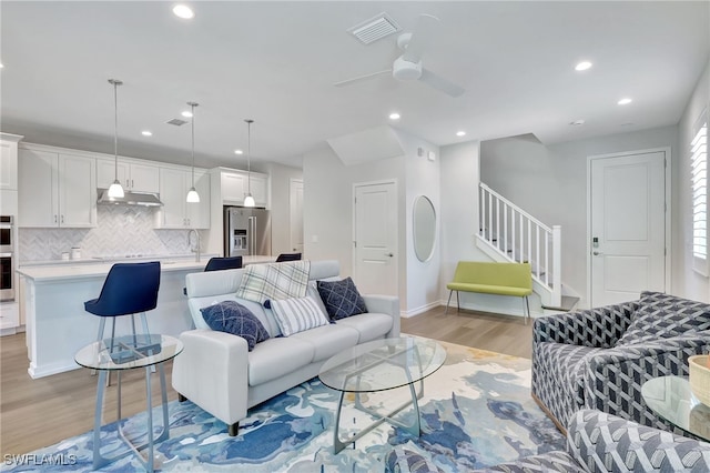 living room with ceiling fan, sink, and light hardwood / wood-style flooring