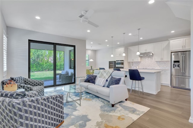 living room featuring light hardwood / wood-style floors, ceiling fan, and sink