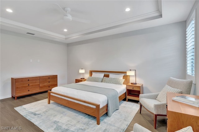 bedroom featuring a tray ceiling, ceiling fan, ornamental molding, and hardwood / wood-style flooring