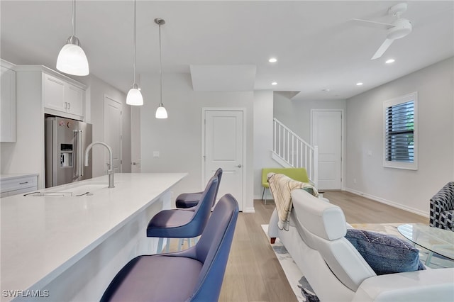 kitchen featuring white cabinets, hanging light fixtures, light hardwood / wood-style flooring, ceiling fan, and high quality fridge