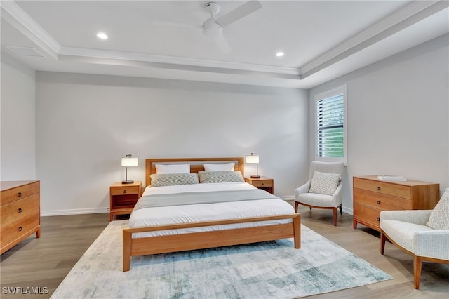 bedroom with a tray ceiling, ceiling fan, crown molding, and hardwood / wood-style flooring