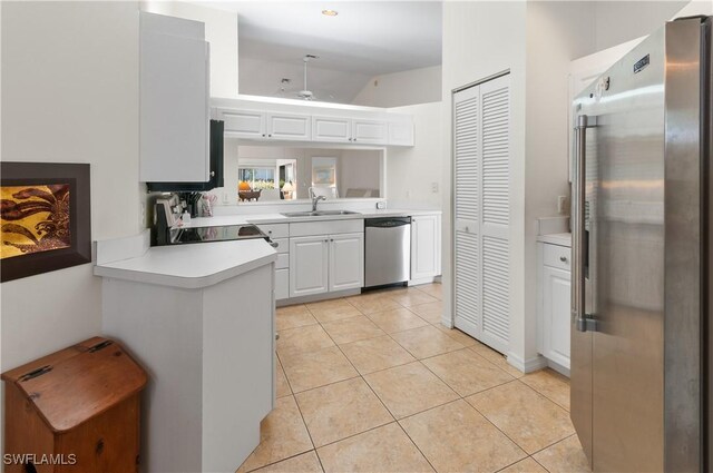 kitchen featuring white cabinets, sink, light tile patterned floors, kitchen peninsula, and stainless steel appliances