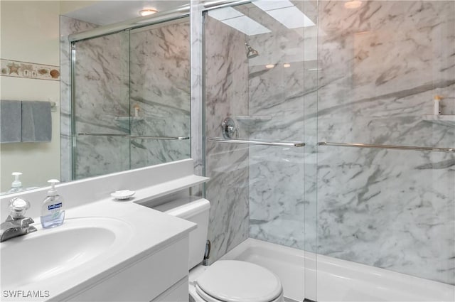 bathroom with vanity, a skylight, toilet, and an enclosed shower