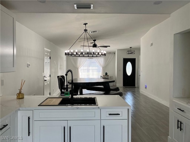 kitchen featuring dark hardwood / wood-style flooring, white cabinetry, sink, and decorative light fixtures